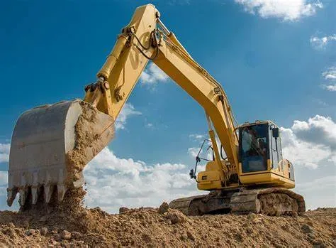 Tracked excavator lifting a bucket of dirt on a rural site