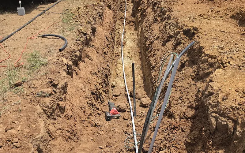 Open trench with conduit laid in it on a Jacksboro Services job