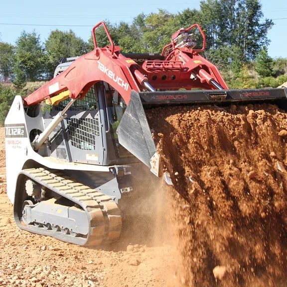 Takeuchi track loader cutting into a dirt bank
